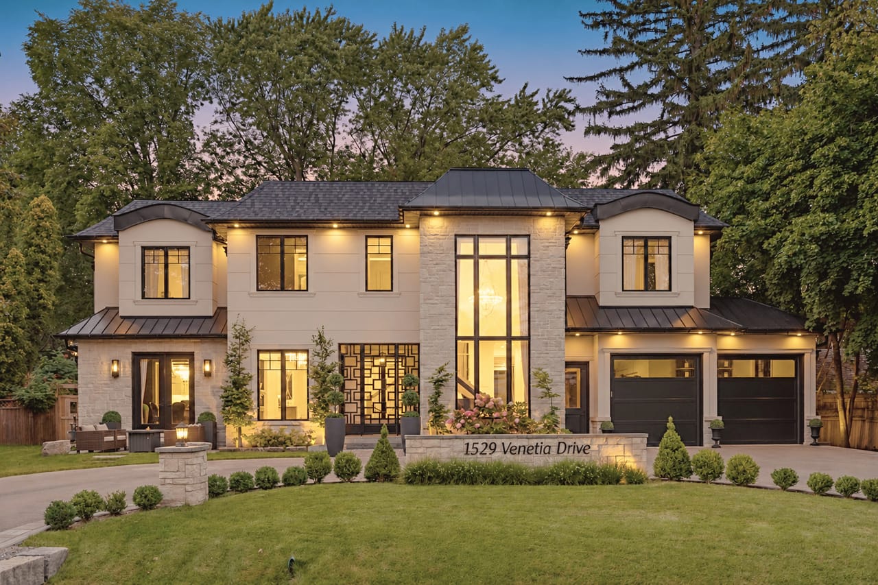 1529 Venetia Drive at twilight, the stone and stucco facade lit from within above the engraved address wall