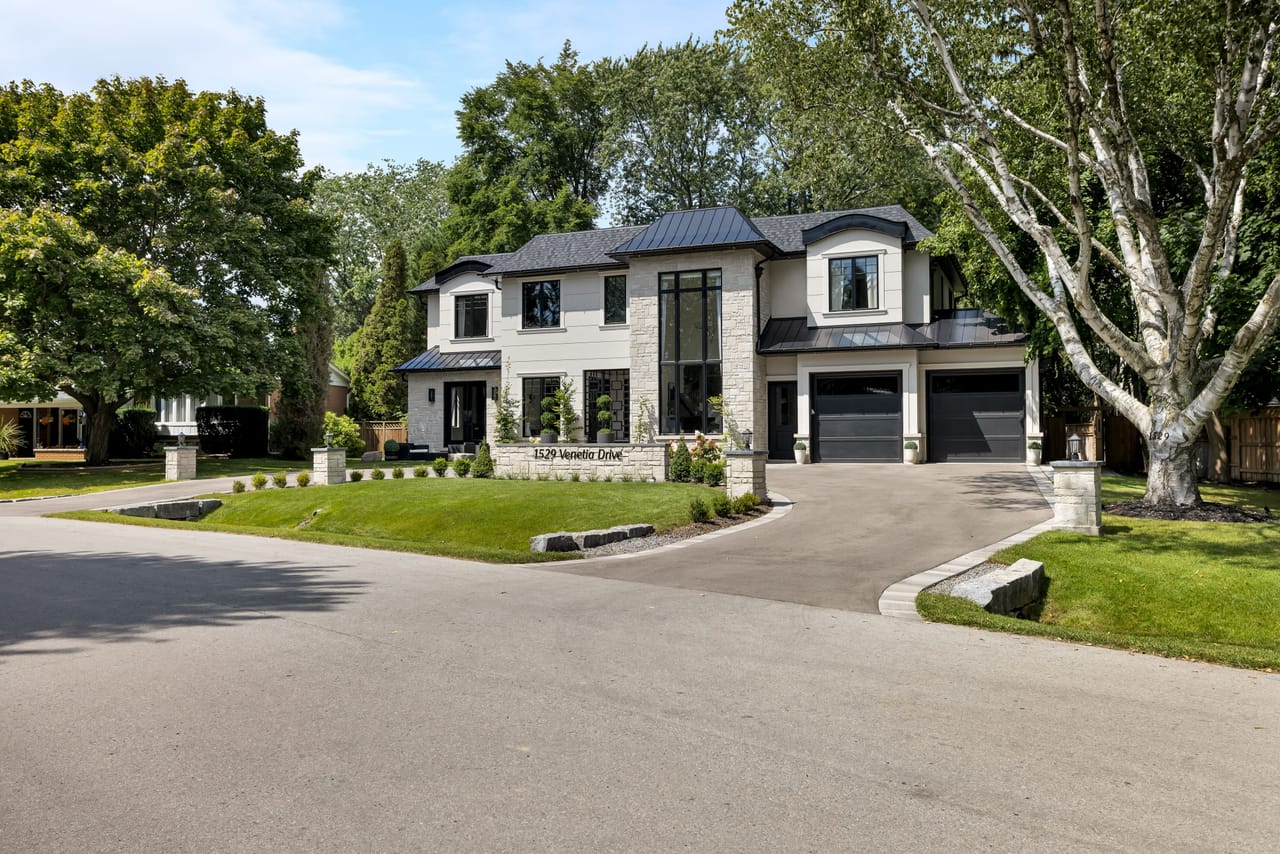 Daytime street view of the estate, its stone and stucco facade set among mature trees