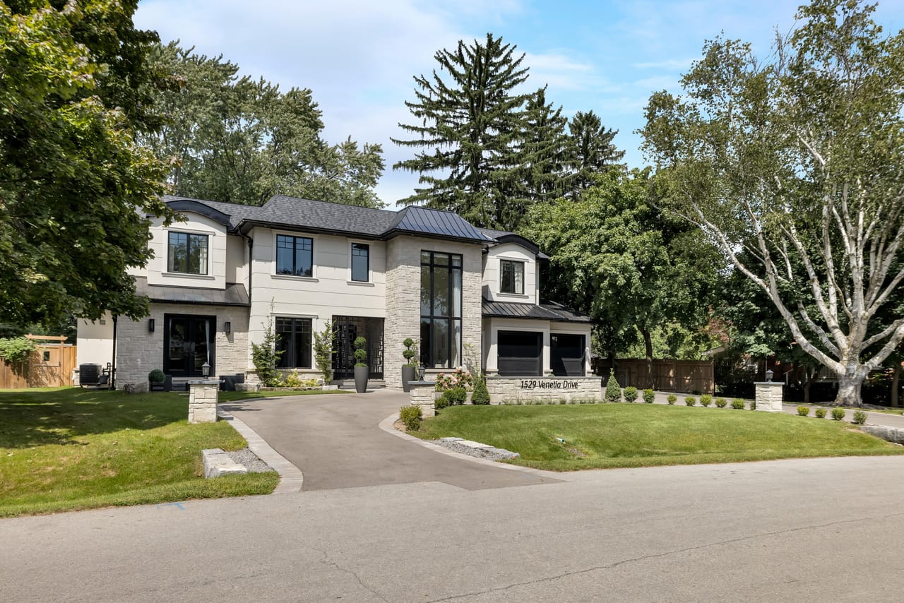 Full front elevation in daylight, with a circular driveway and landscaped lawn