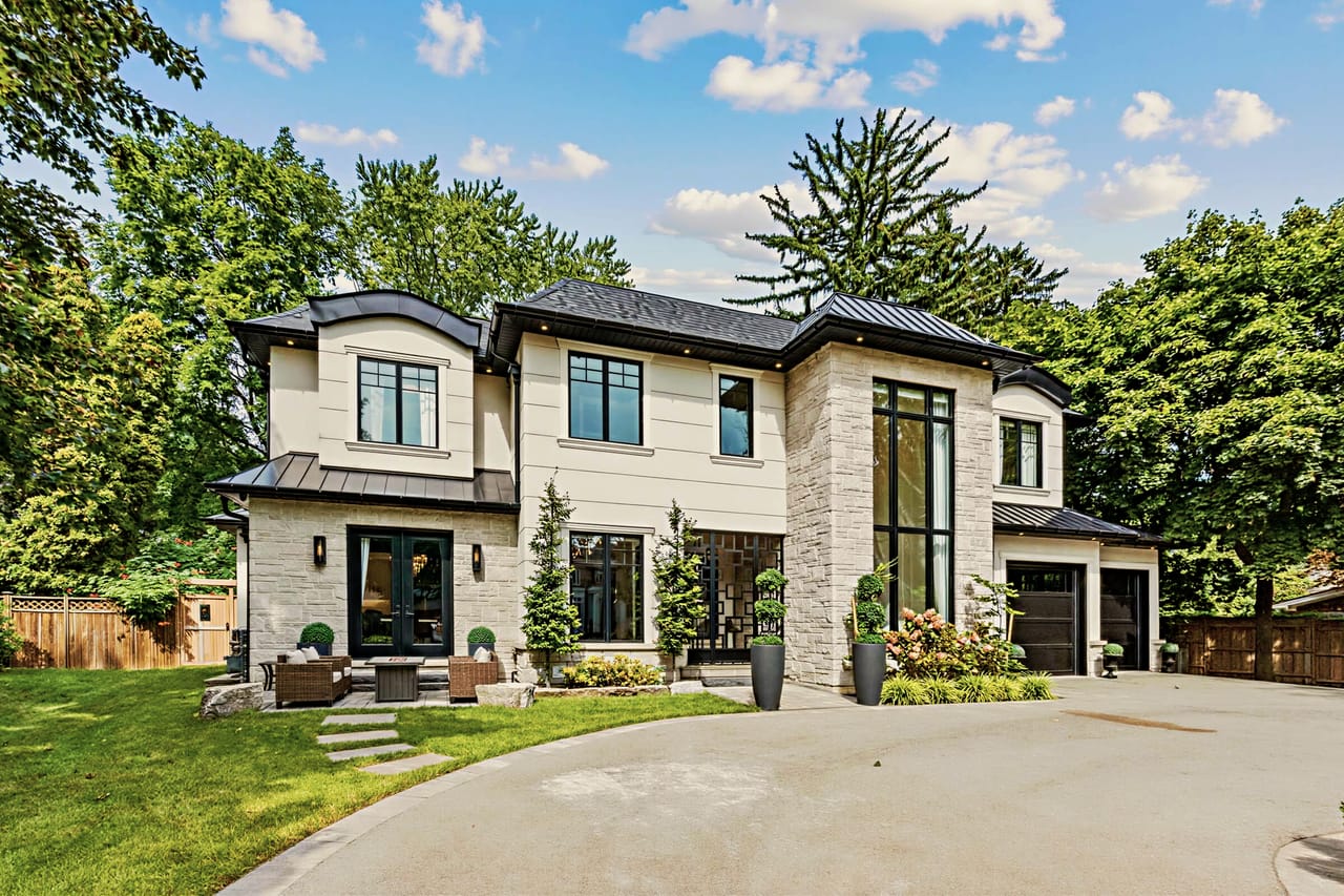 Front elevation from the left, stone base and standing-seam metal roof over the entry wing