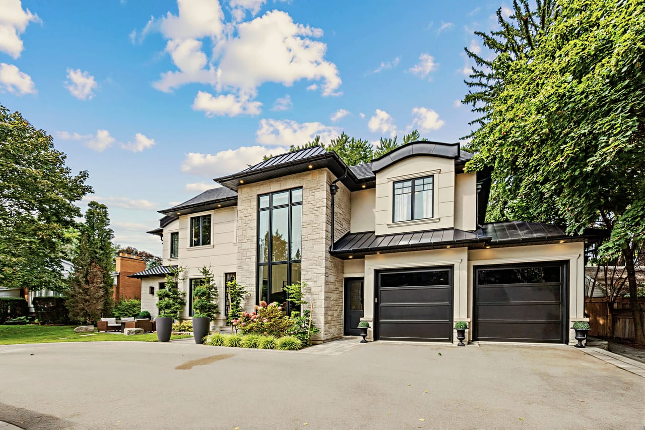The estate angled from the drive, black-framed windows set into limestone and stucco