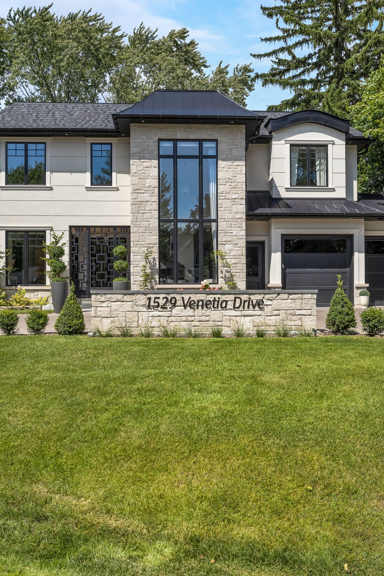 Stone facade and double-height entry window rising above the engraved address wall