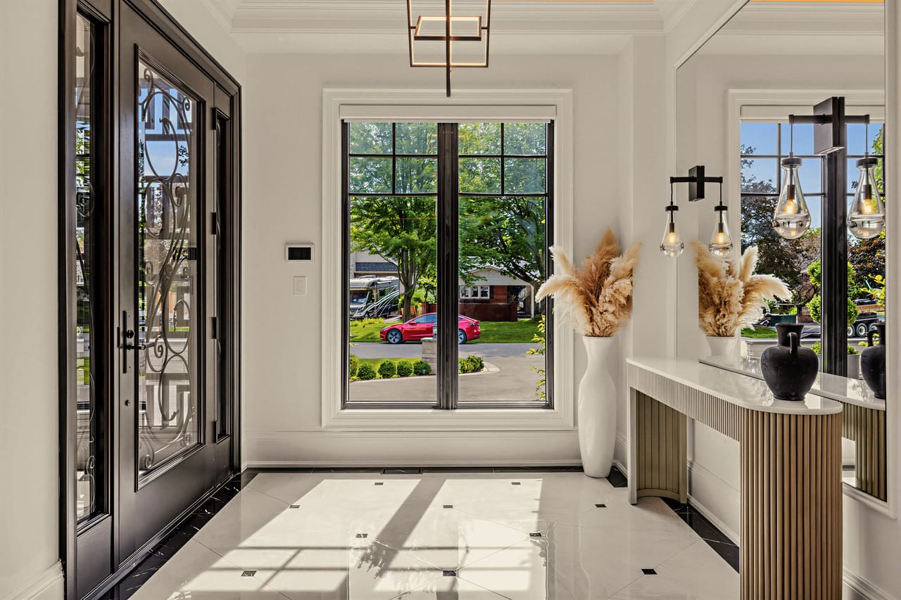 Entry vestibule looking back to the iron and glass front doors across polished stone floors