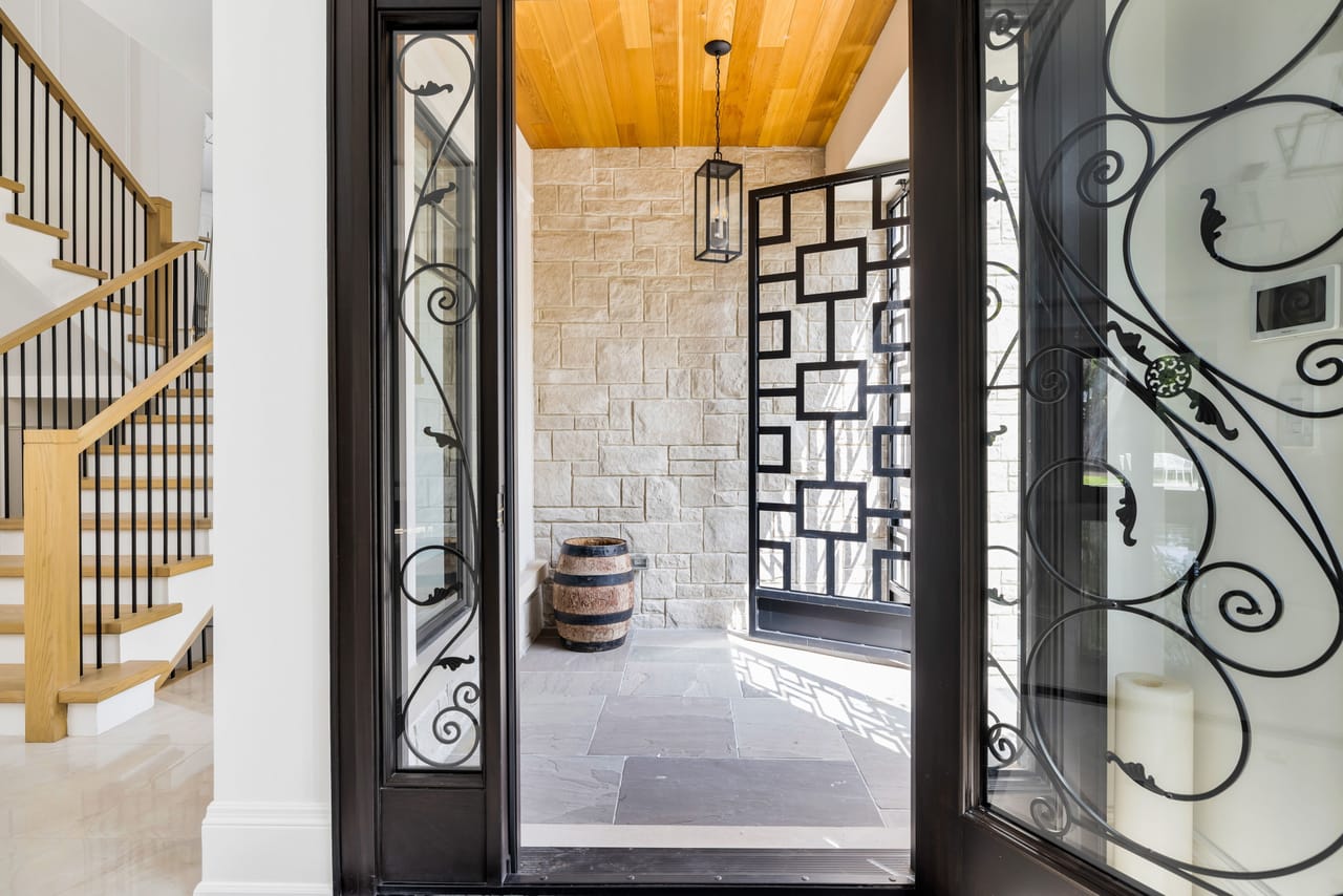 Foyer framed by a wrought-iron and glass front door, with the oak staircase alongside