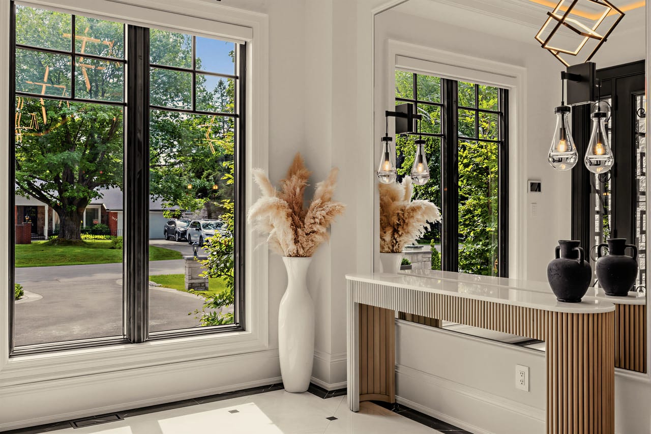 Fluted oak console in the entry, pampas grass and blackened vases against tall windows