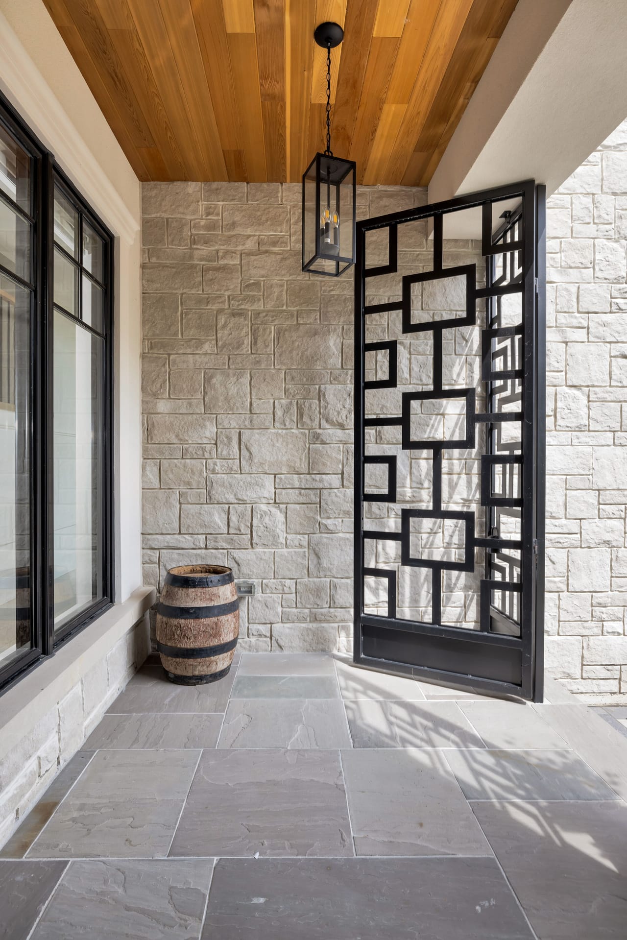 Covered front porch with a cedar-slat ceiling, lantern pendant, and flagstone floor