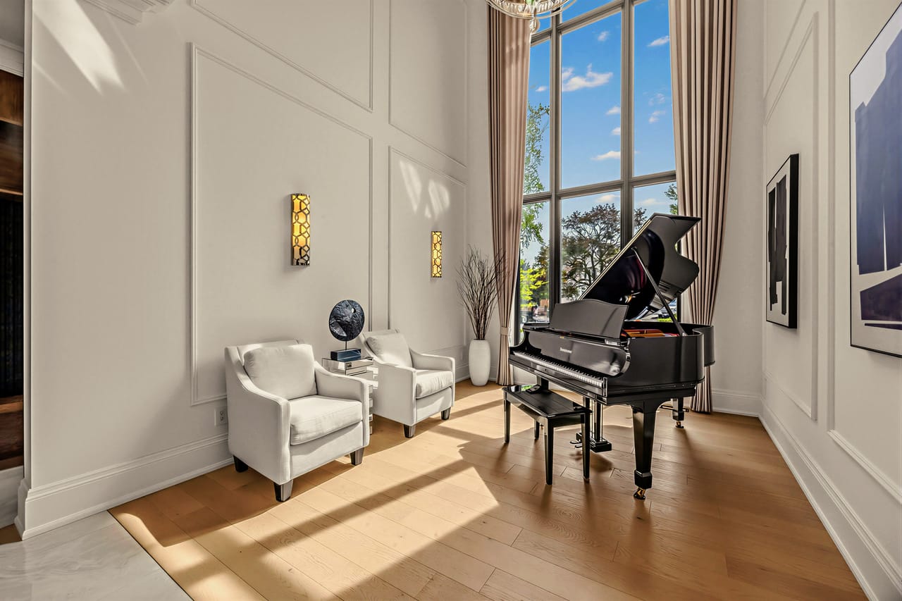 Grand piano on the panelled wall of the music room, afternoon light across the floor
