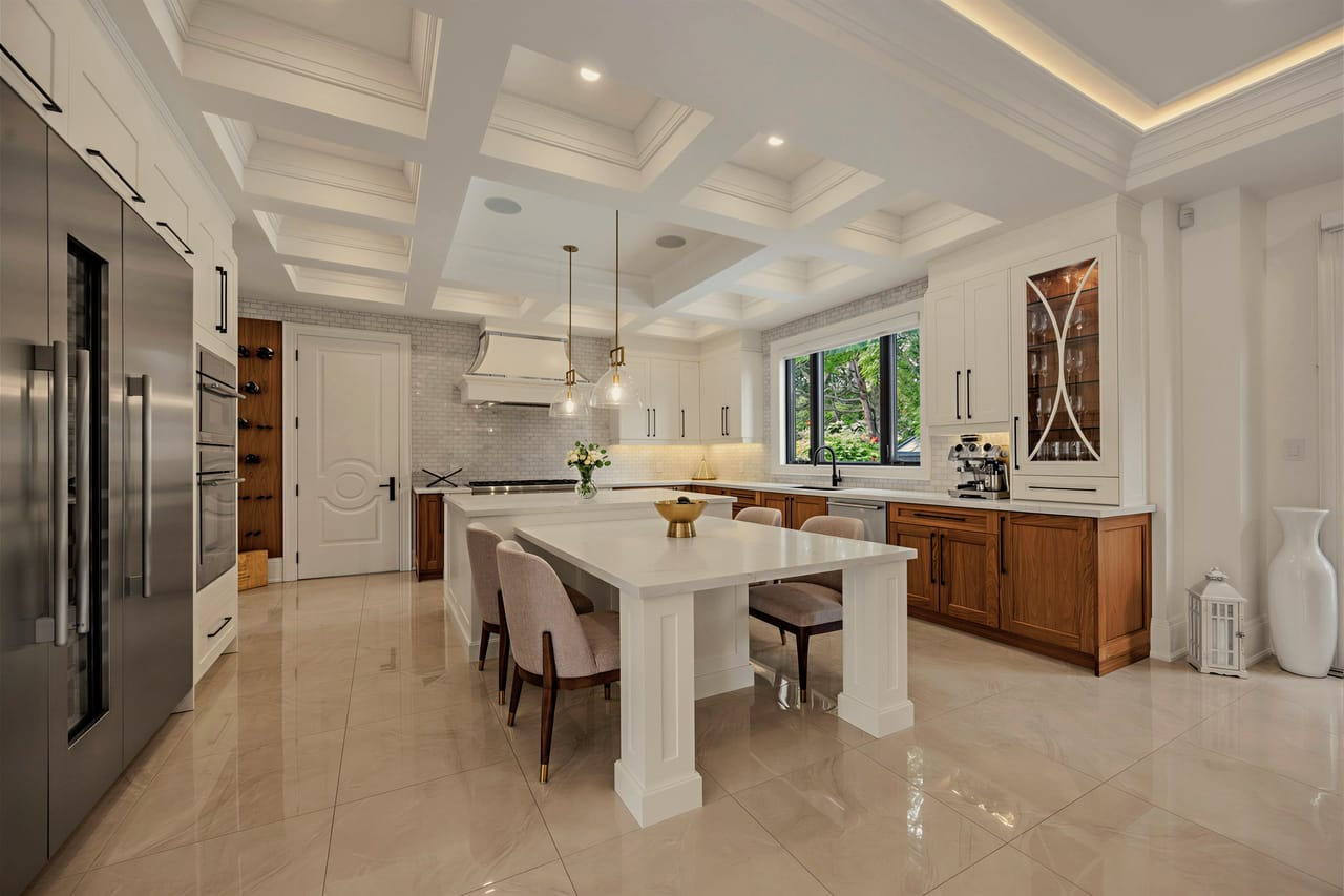 Kitchen under a coffered ceiling, quartz island seating four beneath pendant lights