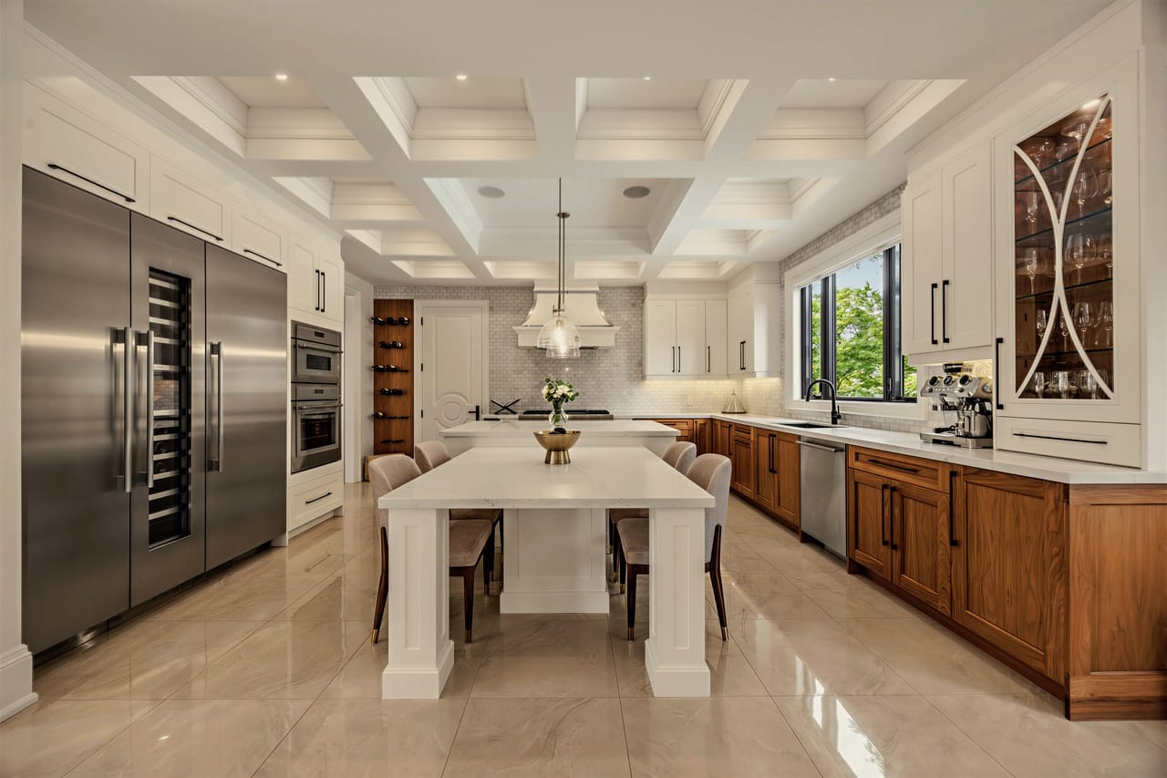 Integrated refrigerator and freezer columns beside the island under the coffered ceiling