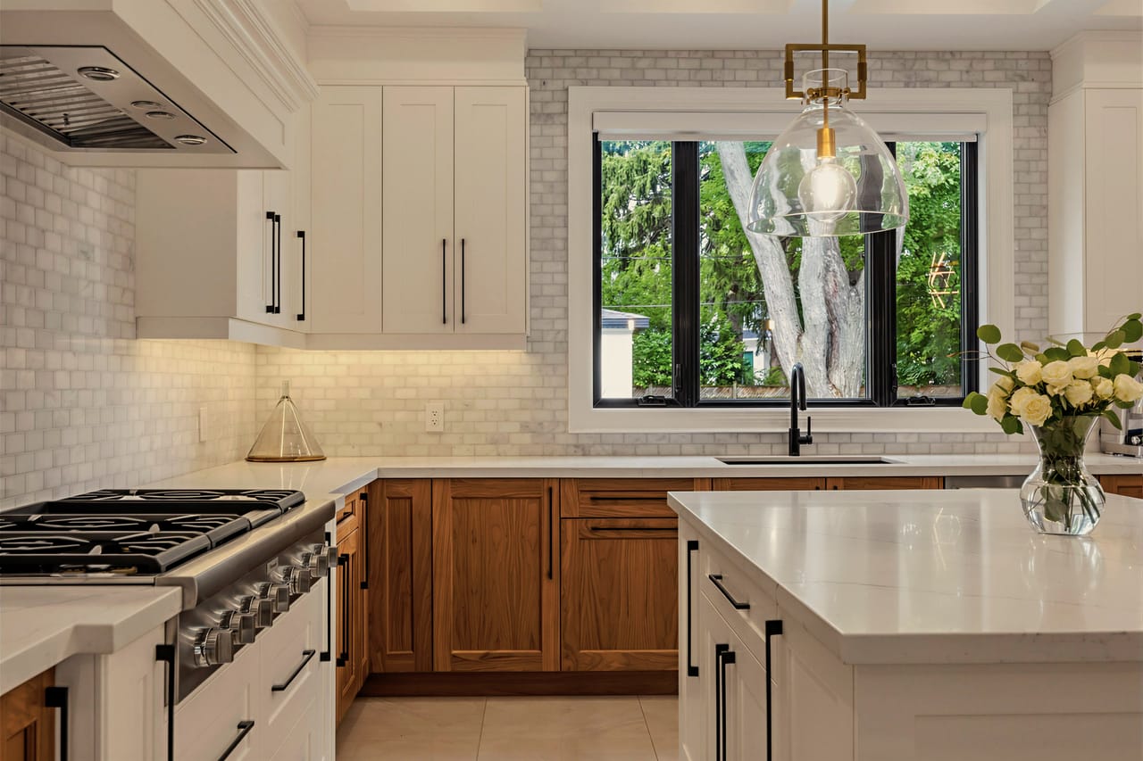 Gas range and hood beneath a window framing the garden, handmade tile to the ceiling