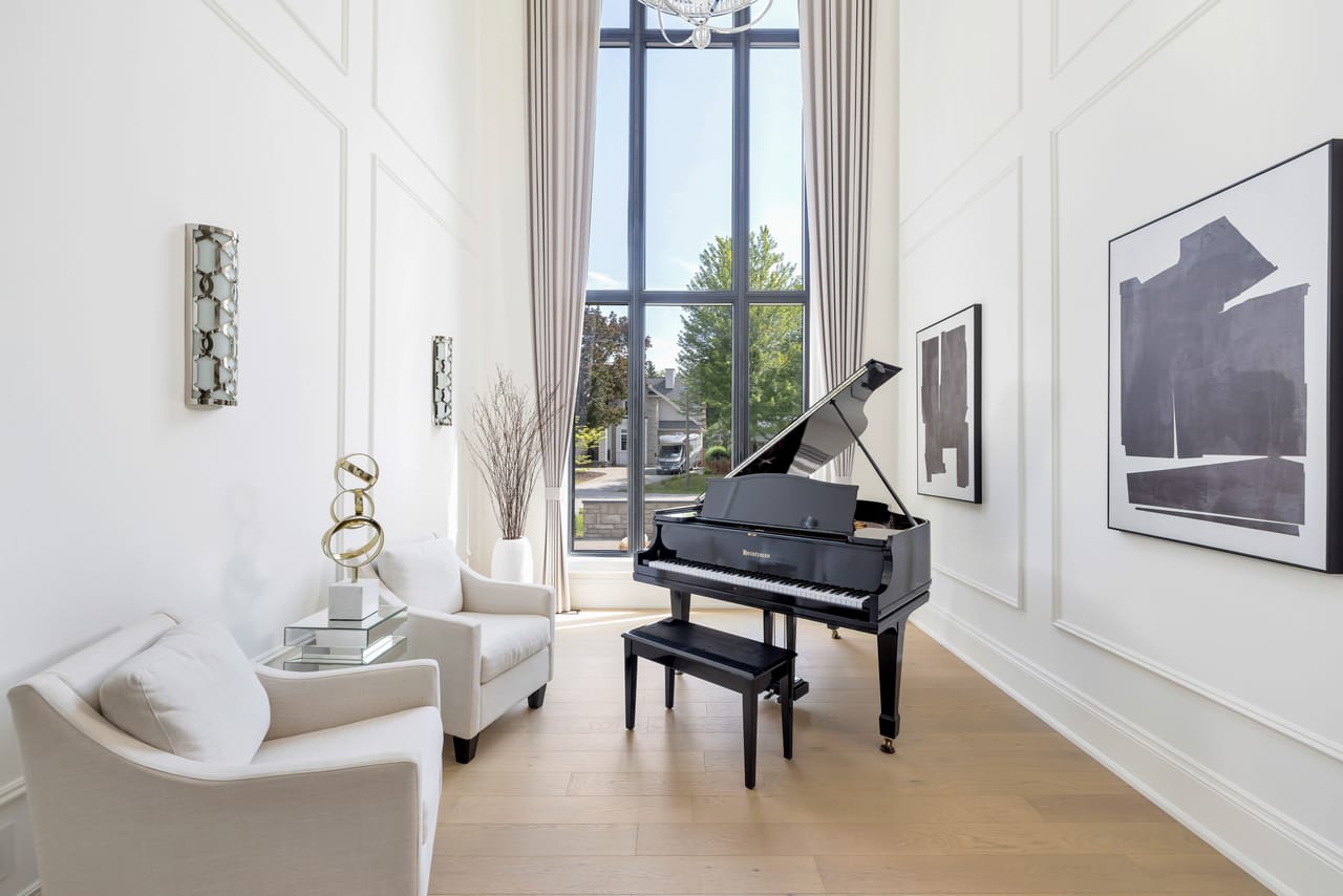 Music room with a grand piano beneath double-height wainscoted walls and a tall window