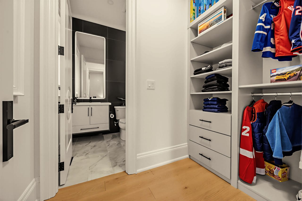 Fitted closet with open shelving, leading into a private ensuite