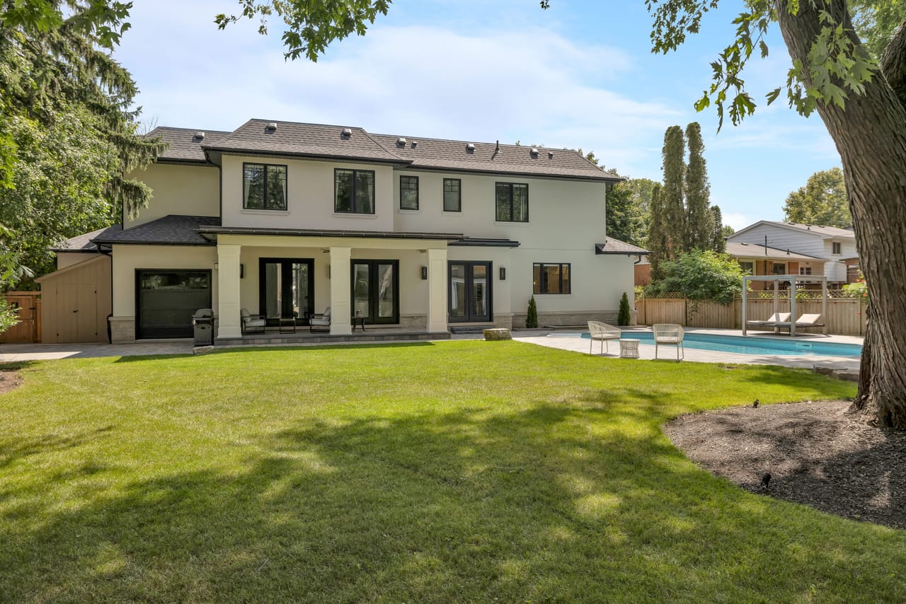 Daytime rear view, the loggia and pool set against mature trees