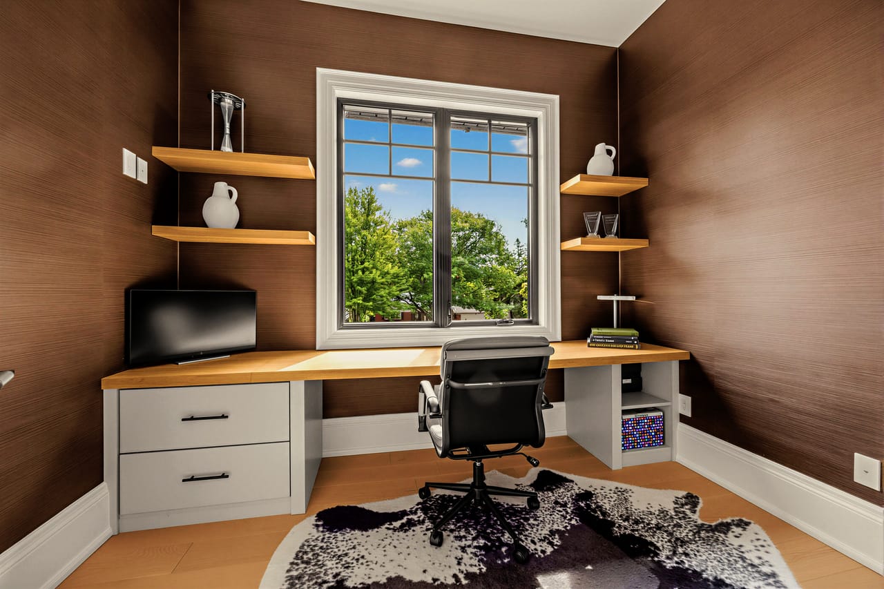 Study with a built-in oak desk wrapping the window and a walnut feature wall