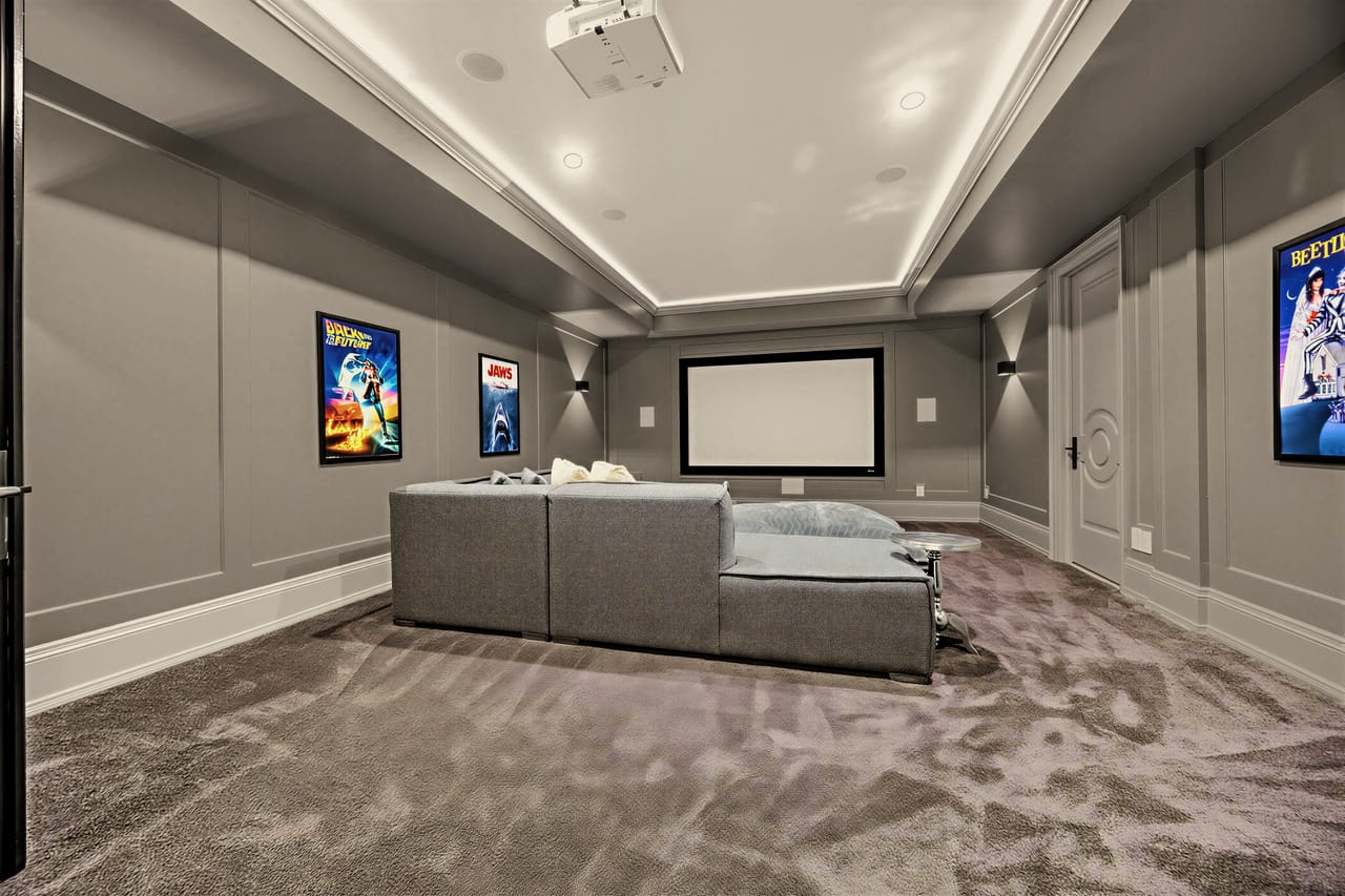 Home theatre with a projection screen, tiered seating and framed film art