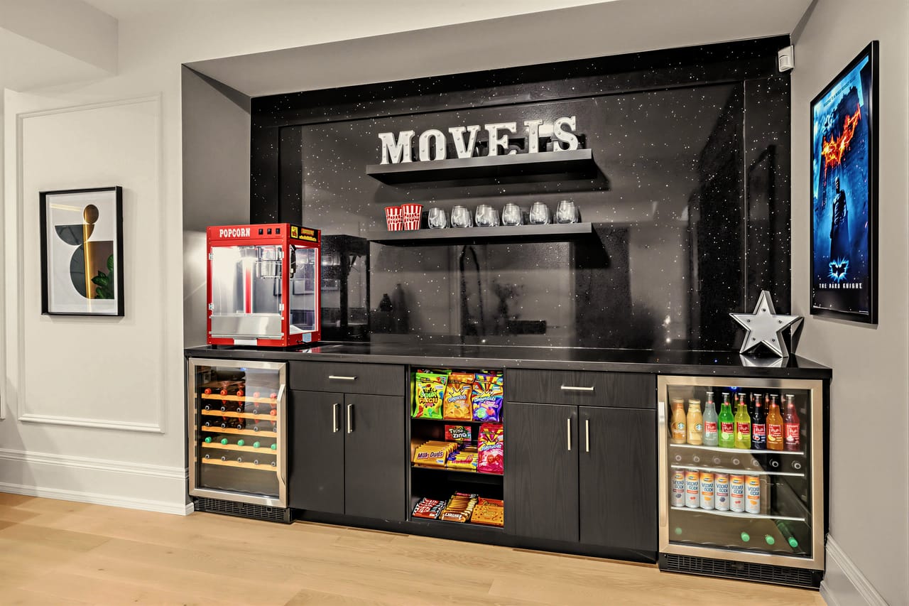 Concession bar with a popcorn machine, beverage fridges and a backlit marquee