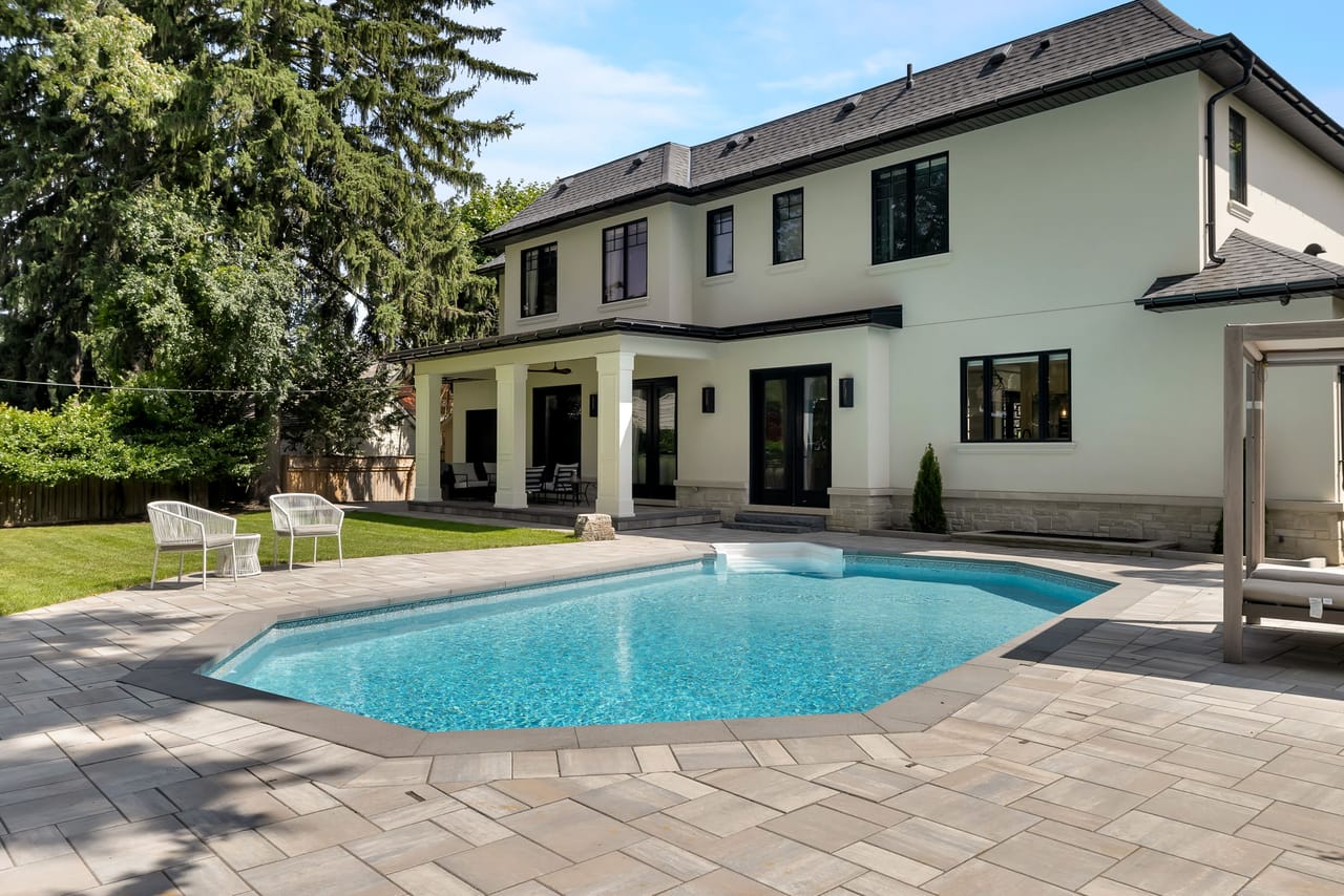 In-ground pool and paver deck beneath the full rear elevation