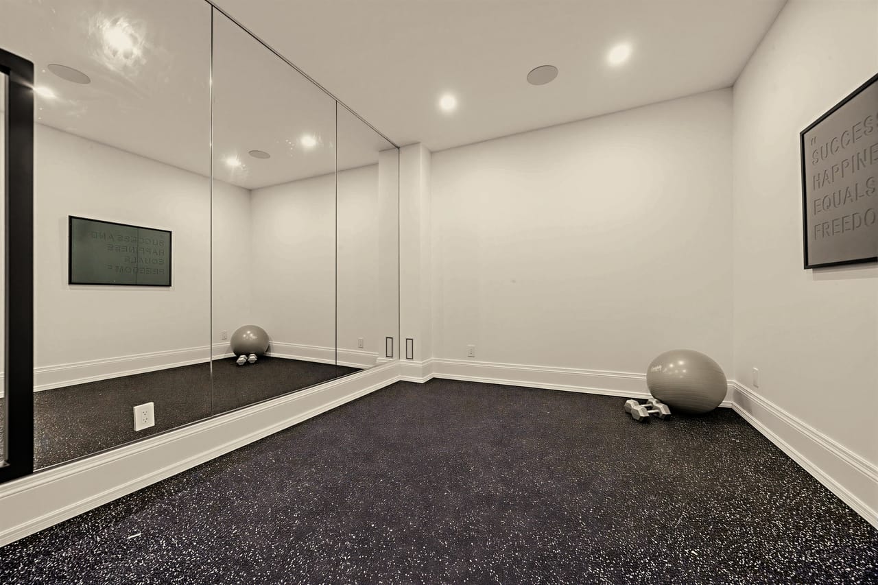 Mirrored gym with a cushioned training floor and a full wall of glass