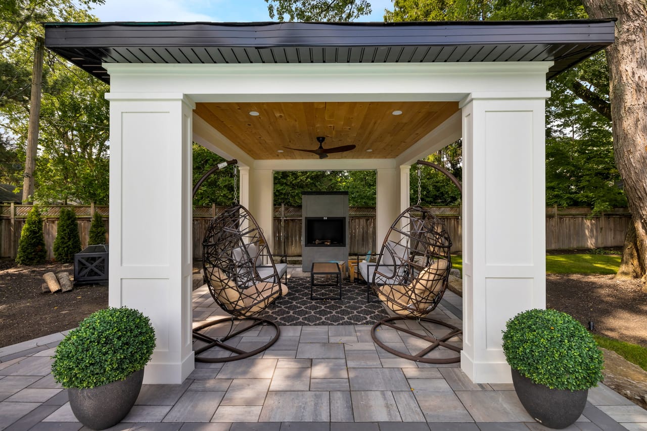 Poolside cabana with hanging chairs, a ceiling fan, and an outdoor television