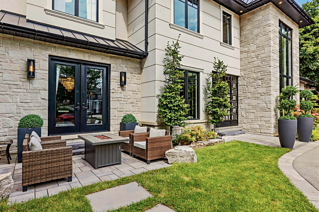 Side terrace beside the lawn, fire table and lounge seating against the stone facade