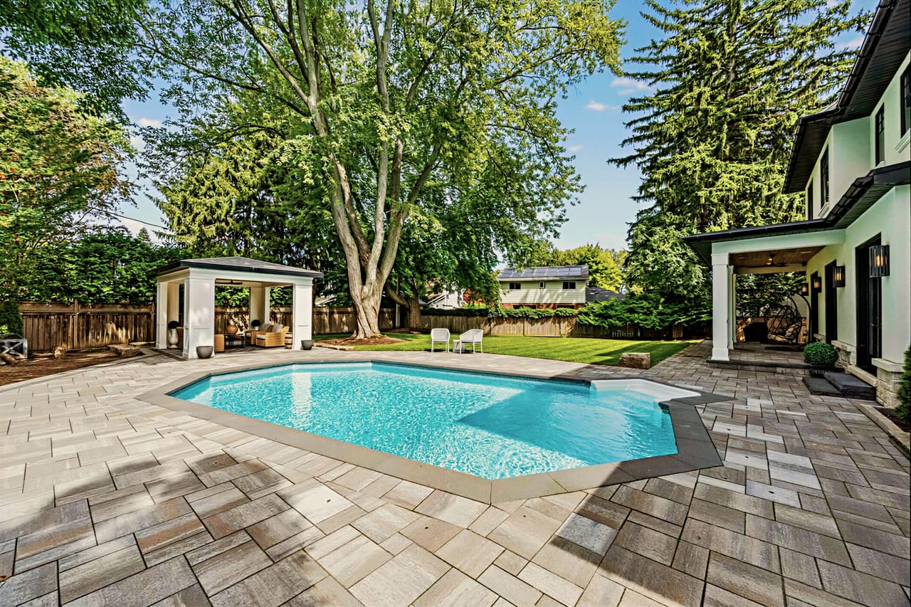 The pool from the lawn, wrapped in a wide banded-stone surround