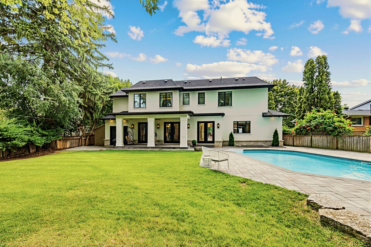 The back of the property in full, level lawn between the house and the pool