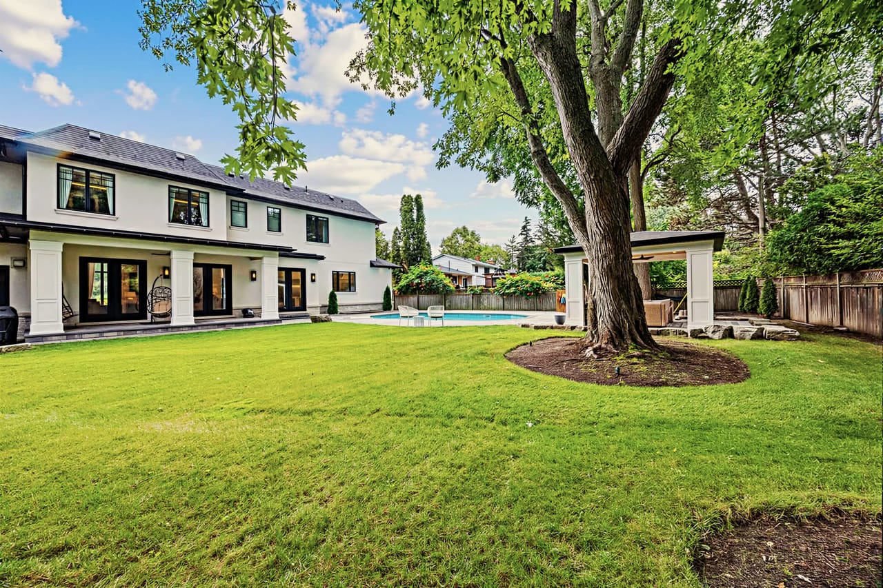 Rear garden framed by a mature maple, the home beyond the open lawn