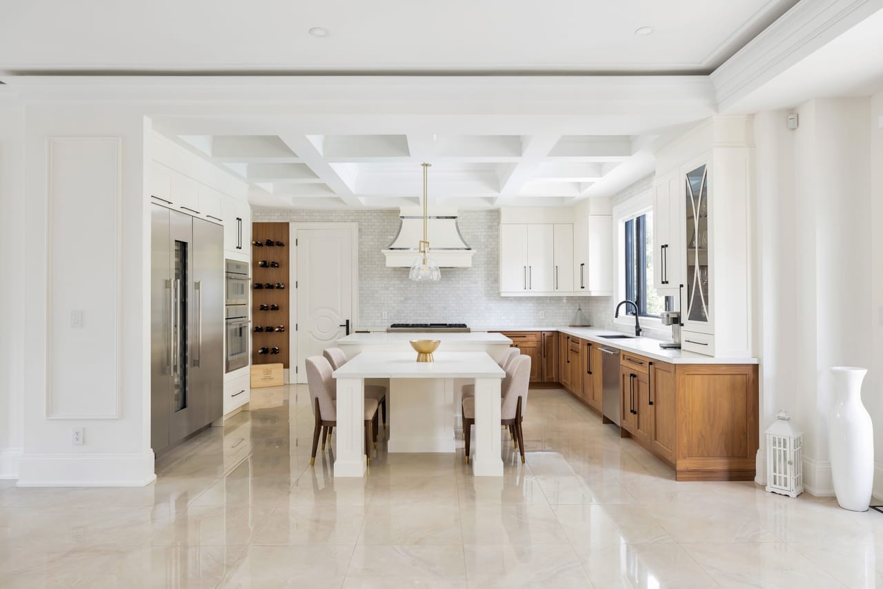 Chef's kitchen with a coffered ceiling, marble island, walnut cabinetry, and built-in refrigeration