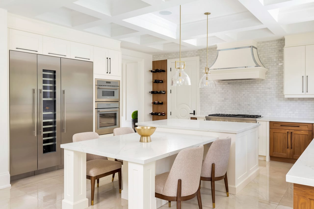 Kitchen overview with paired islands, full-height refrigeration, double wall ovens, and a wine display