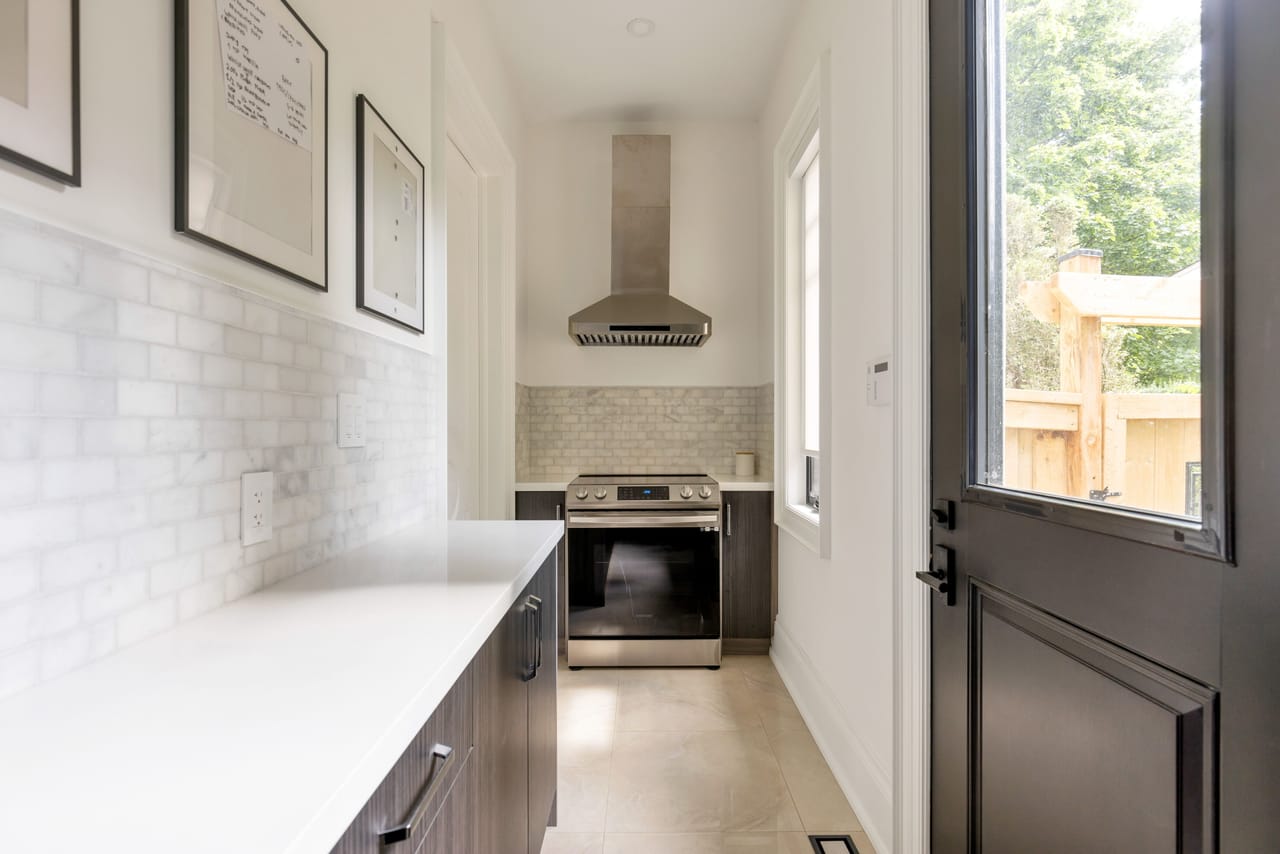 Catering kitchen with a second range, marble backsplash, and direct access to the rear yard
