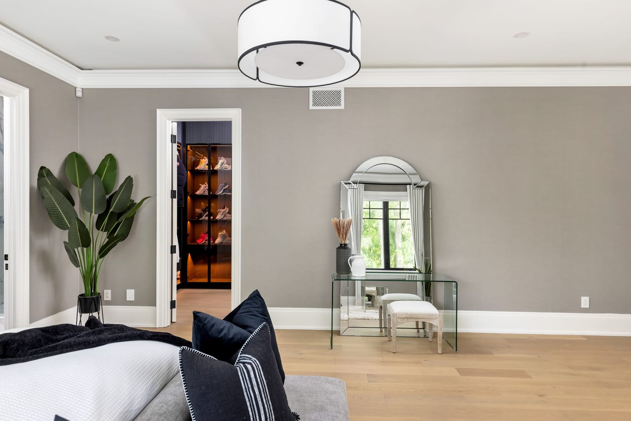 Primary bedroom with a glass vanity and a view into the fitted dressing room