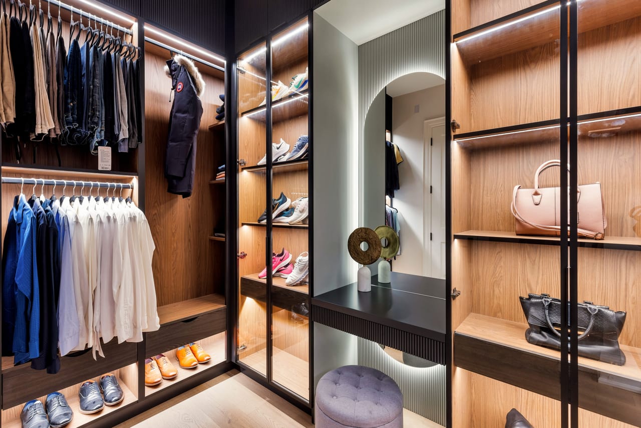Boutique-style dressing room with oak shelving, integrated lighting, and a backlit mirror