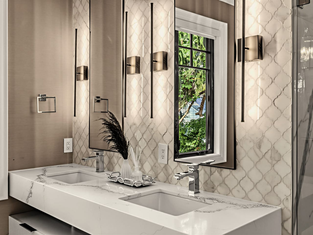 The primary ensuite vanity, twin basins under sconces and a garden window