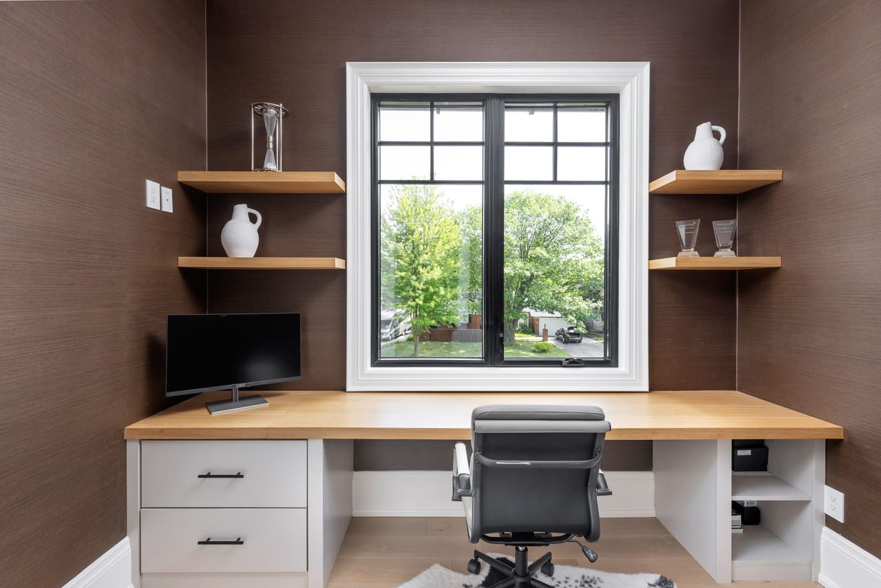 Home office wrapped in grasscloth, with a built-in desk and floating oak shelves