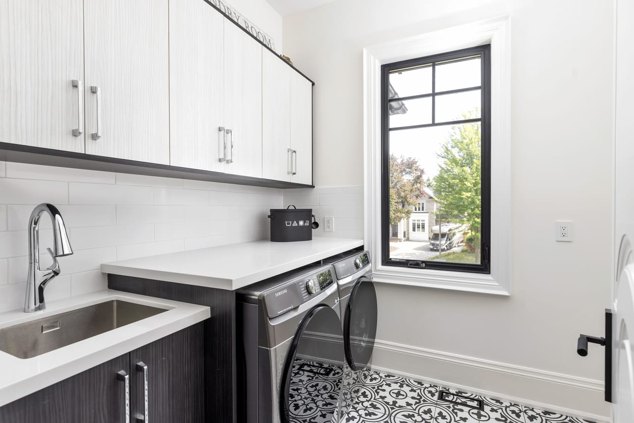 Laundry room with a patterned tile floor, stone counters, and side-by-side machines