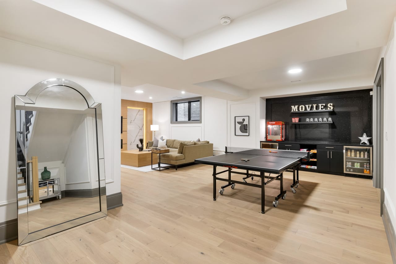 Lower-level recreation room with a games table and a media bar beyond the lounge