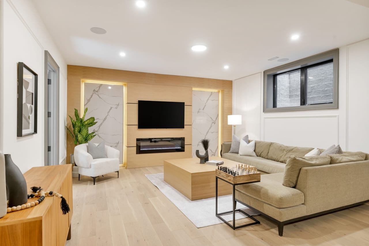 Lower-level lounge with a backlit marble and wood feature wall, fireplace, and sectional