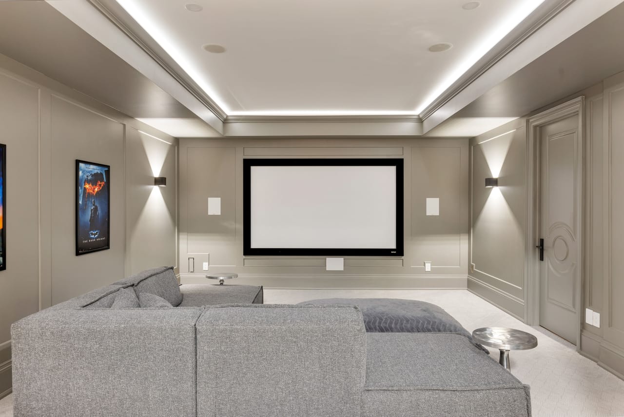 Home theatre with tiered seating facing a wide projection screen