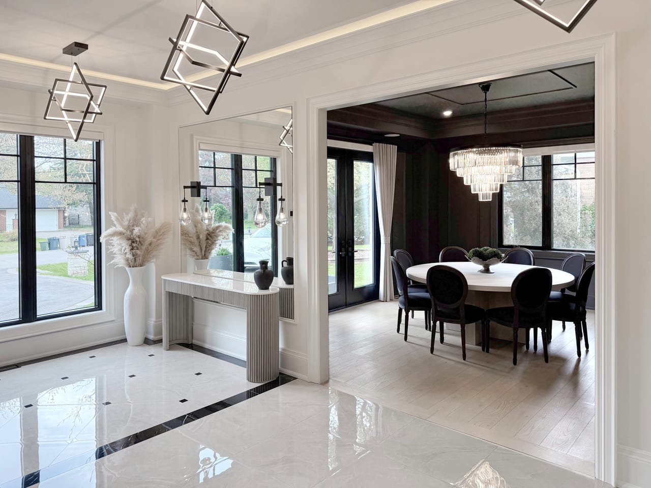 Marble-floored foyer opening to the formal dining room, lit by sculptural pendants